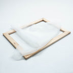 Ein Siebdruckrahmen aus Holz liegend, mit einem Stück Siebdruckgewebe 54T