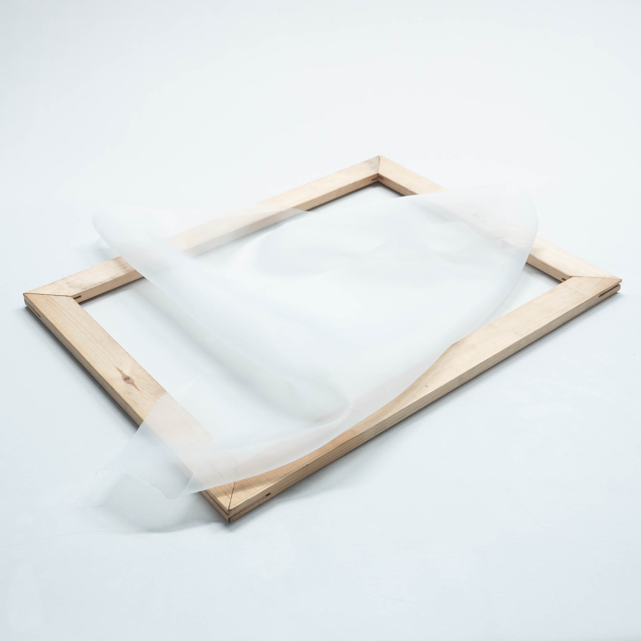 Ein Siebdruckrahmen aus Holz liegend, mit einem Stück Siebdruckgewebe 54T