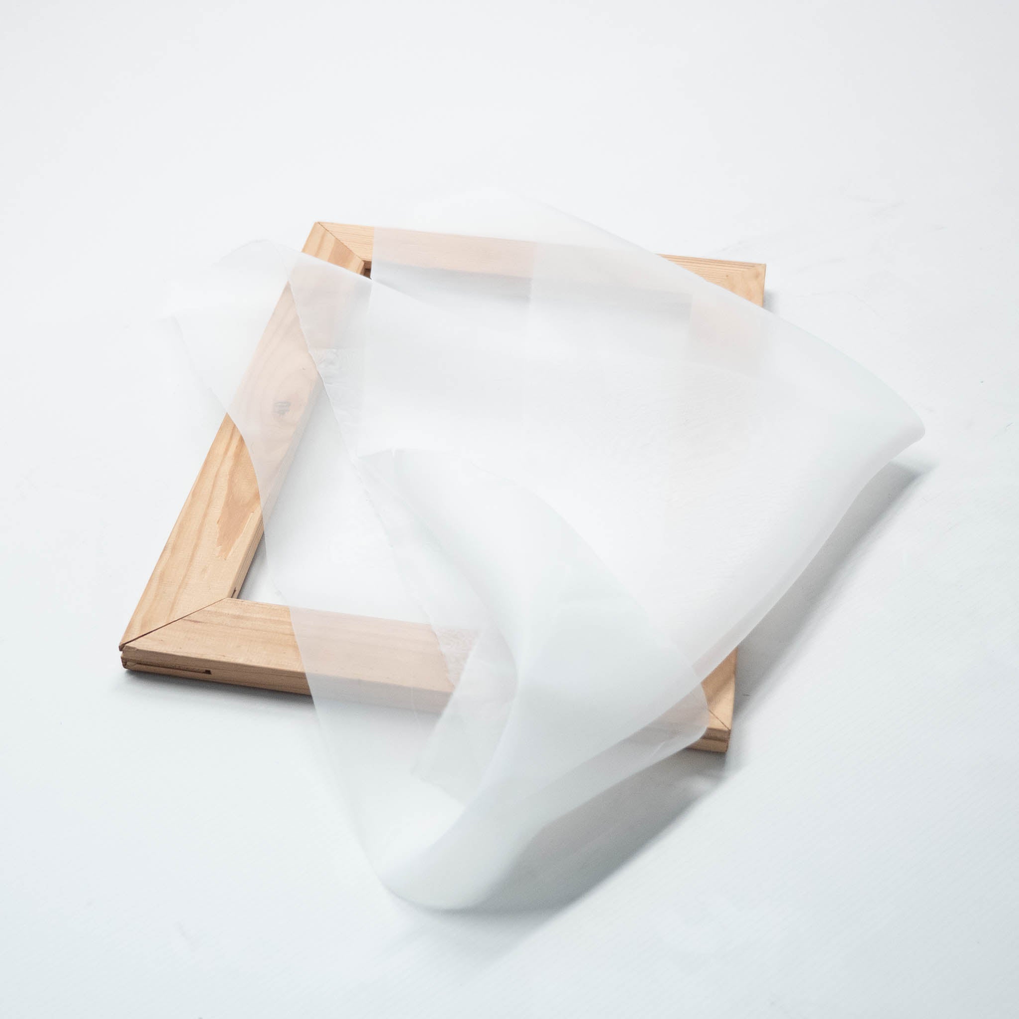 Ein Siebdruckrahmen aus Holz in der Größe A4 liegend, mit einem Stück Siebdruckgewebe 54T