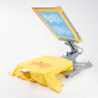 Ein mit dem Logo von Dipilu bedrucktes T-Shirt, auf einer Siebdruckmaschine.