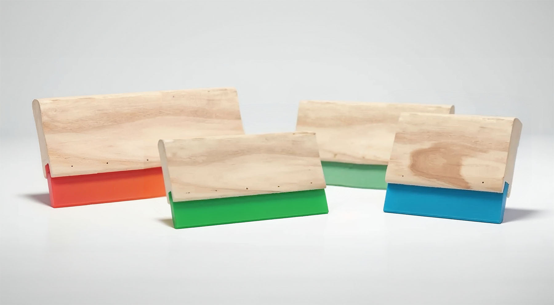 Siebdruckrakel aus Holz in unterschiedlichen Längen mit Gummis in unterschiedlichen Farben.